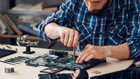 Profissional em estação de trabalho consertando computadores.